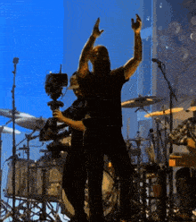 a man in a black shirt is standing on stage with his arms in the air
