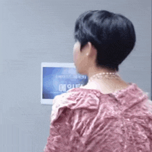 a woman in a pink dress is standing in front of a wall with a sign that says ' a ' on it