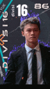 a man in a suit and tie is standing in front of a sign that says divisi 16