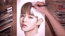 a person is drawing a woman 's face with colored pencils on a wooden table