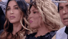 a group of women are sitting in a stadium watching a game .