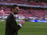 a man in a suit and sunglasses is walking on a soccer field
