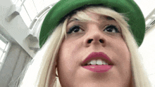 a close up of a woman wearing a green hat and lipstick .