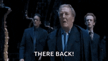 a man in a suit says there back in a dark room