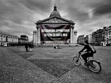 a man riding a bike in front of a building with a banner that says outsourcing appointment setters to costa rica