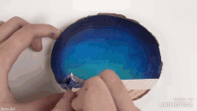 a person is painting a picture on a piece of wood and the words wow art can be seen in the corner