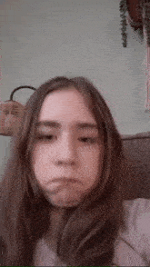 a girl with long hair is making a funny face while sitting on a couch .