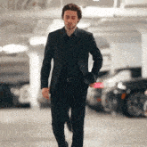 a man in a black suit is walking in a parking garage