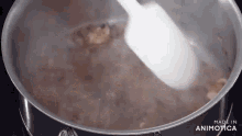 a pot of boiling water with a white spoon in it
