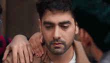 a man with a beard is being comforted by a woman who is holding his shoulder .