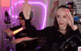 a woman wearing a resident evil shirt holds a light saber in her hand