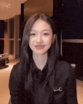 a woman with long black hair is smiling and wearing a black shirt with a key on it .
