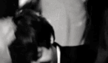 a black and white photo of a man and a woman kissing each other .