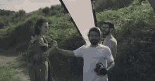 a group of people are standing in a field holding hands and a man is holding a camera .