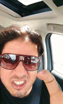 a man wearing sunglasses is making a funny face while sitting in a car