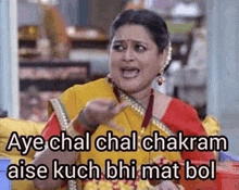 a woman in a yellow saree is sitting on a couch and making a funny face while eating food .