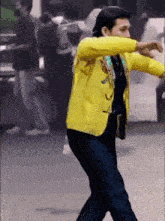 a man in a yellow jacket and blue jeans is dancing on the street