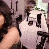 a woman is sitting in a white akracing gaming chair