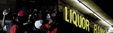 a group of people standing in front of a liquor bank
