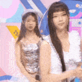 two women are standing next to each other on a stage and one of them is wearing a hat .