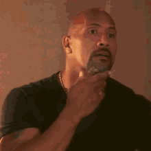 a bald man with a beard is holding his hand to his chest and making a funny face .