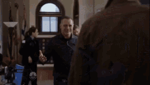 two men are standing next to each other in a room and hugging each other .