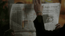 a person is reading the angeles telegraph newspaper and giving it a high five