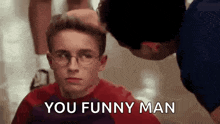 a man is giving a boy a haircut and says `` you funny man '' while the boy looks at him .