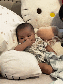 a baby laying on a bed next to a hello kitty