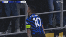 a soccer player stands in front of a fence with a sign that says port