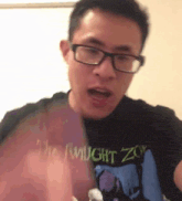 a man wearing glasses and a twilight zo t-shirt is making a face .