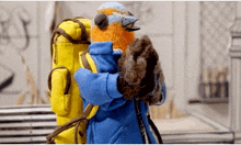 a stuffed bird is holding a yellow backpack