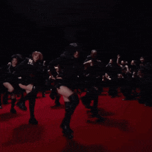 a group of women are dancing on a red carpet in front of a crowd