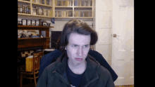 a man sitting in front of a bookshelf with a shelf full of books on it