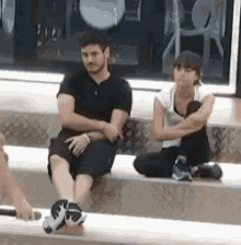 a man and a woman are sitting on a bench with their legs crossed .