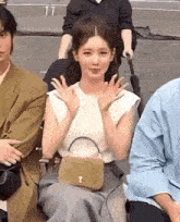 a woman is sitting in a chair with her hands up and a purse on her lap .