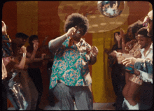 a man in a colorful shirt is dancing in front of a disco ball that says ' s-way ' on it