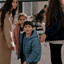 a boy in a blue jacket is standing next to two girls