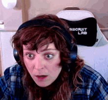 a woman wearing headphones with the word secret lab on the back