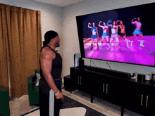 a man stands in front of a television watching a video