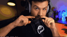 a man wearing headphones holds his finger to his mouth in front of a microphone that has the letter s on it