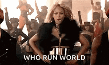a woman in a black dress is dancing in front of a crowd .