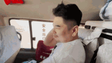 a man sits in the back seat of a car with chinese writing on the window