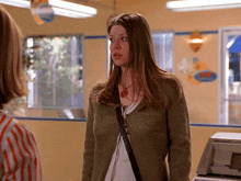 a woman in a green cardigan stands in a room