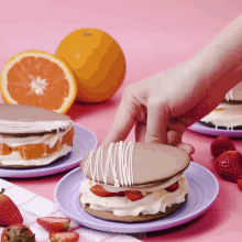 a person is reaching for a strawberry sandwich on a plate
