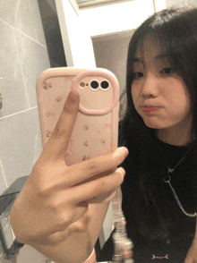 a girl is taking a selfie with her phone in a pink case