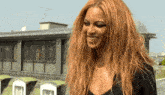 a woman with long red hair is smiling and wearing a black shirt