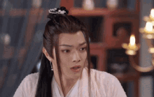 a man with long hair and a crown on his head is wearing a pink robe and earrings .