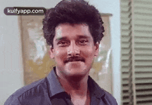 a man with a mustache is making a funny face and smiling .
