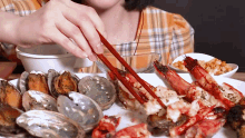 a woman is eating seafood with chopsticks while sitting at a table .